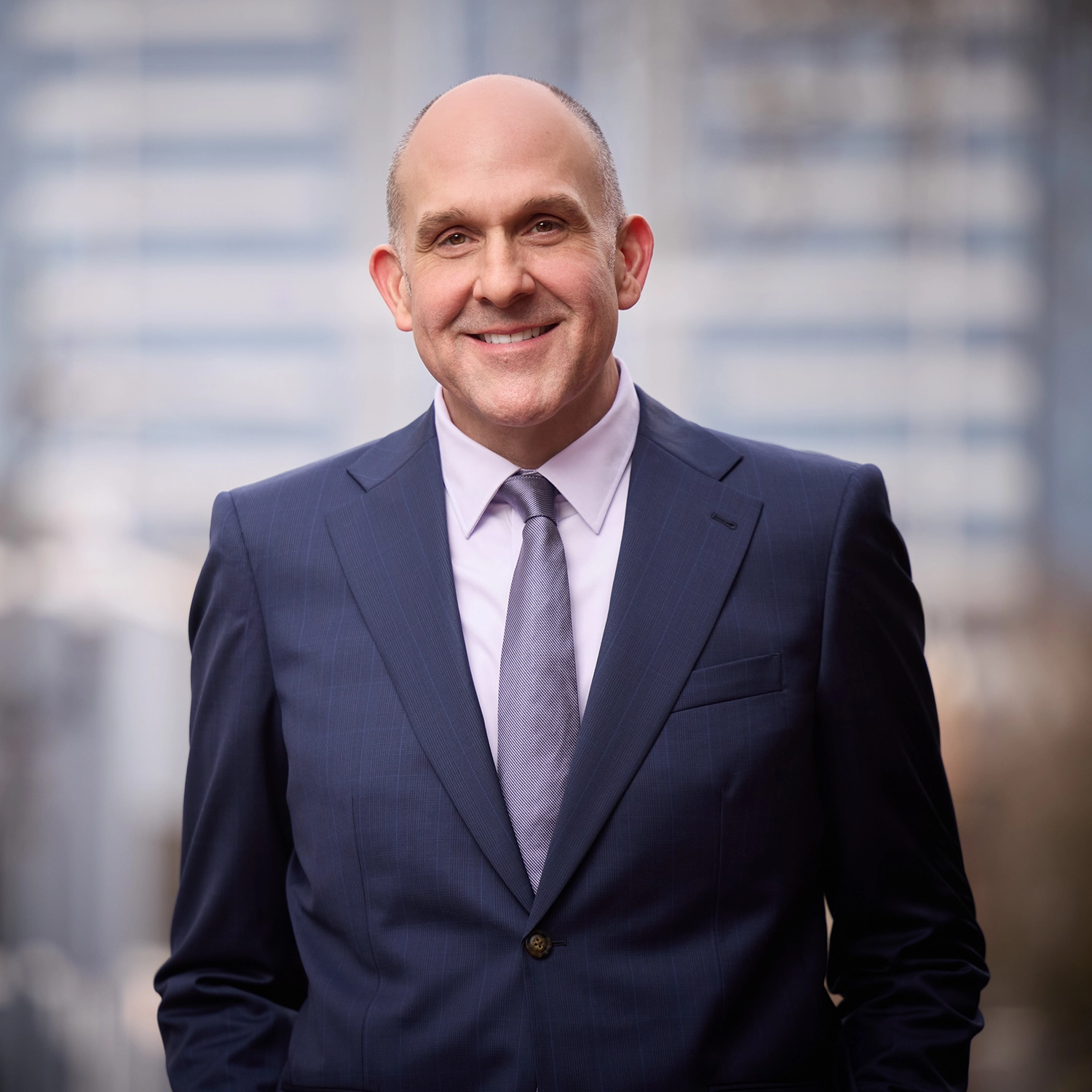 Compassion & Choices Action Network's President and CEO Kevin Diaz standing in front of a blurry metropolitan backdrop.