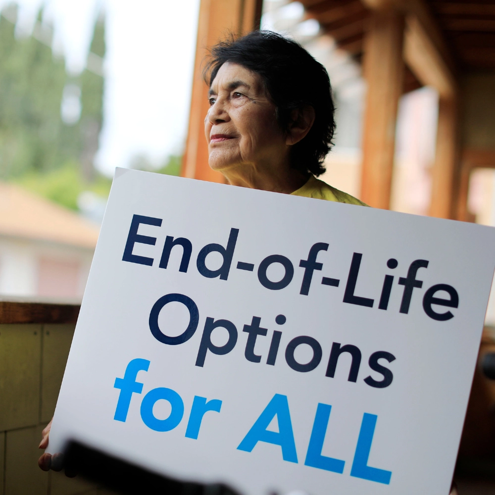 Dolores Huerta holding a sign saying "End-of-Life Options for ALL"